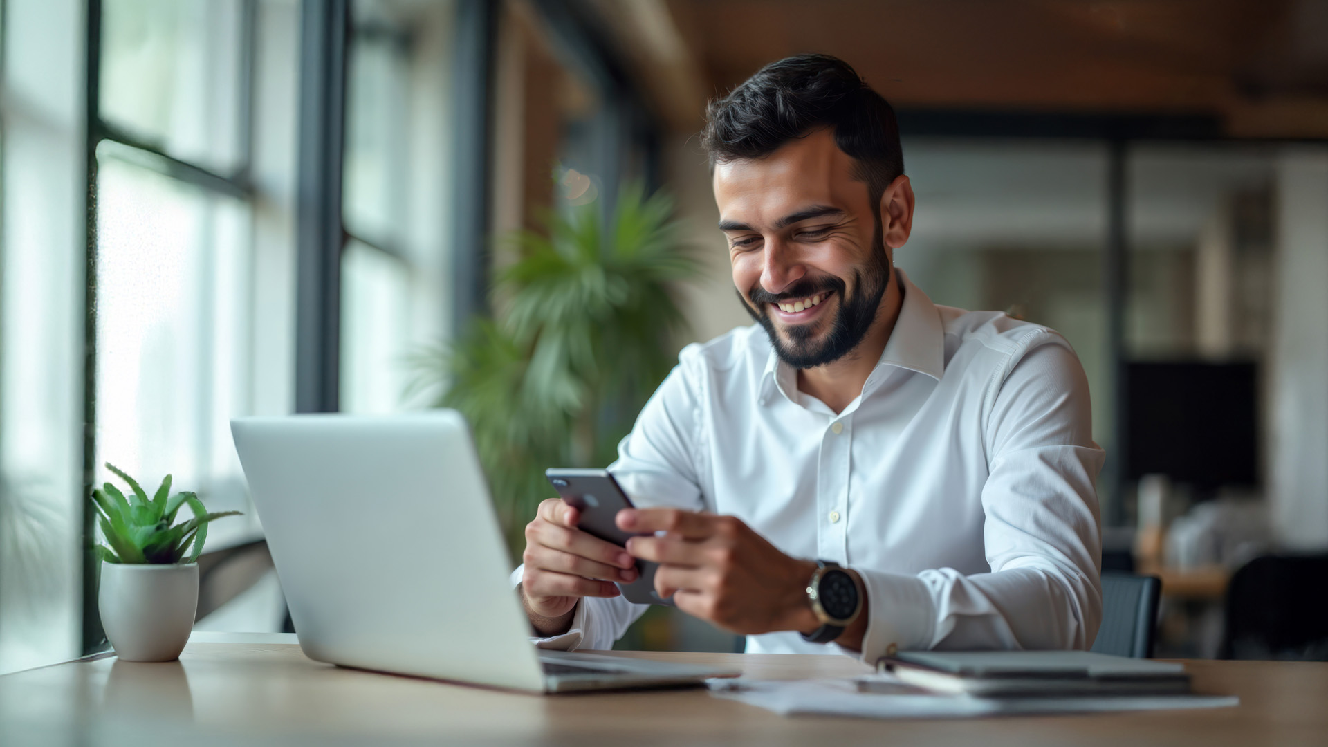 uomo alla scrivania con laptop e mobile phone